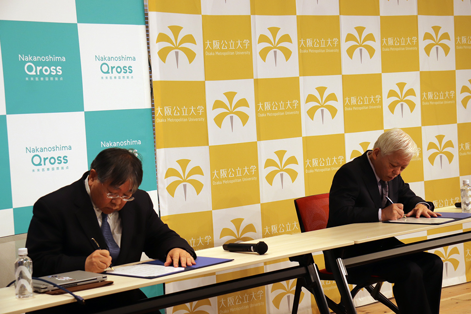 写真：協定書にサインをする二人